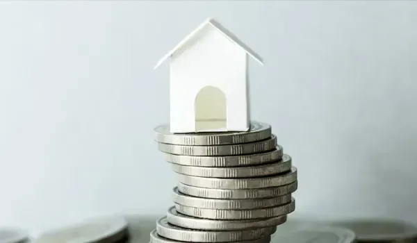 Casa en miniatura sobre monedas, símbolo de ahorro en hipotecas en Málaga con asesoría de bróker hipotecario