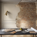 Salón residencial a medio reformar con muestrarios de materiales sobre mesa y ladrillo visto a la vista