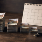 Pilas decrecientes de billetes de cien euros junto a un calendario y una pluma estilográfica sobre madera
